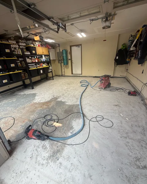 Before: stained concrete garage floor during grinding, with shelving along the wall