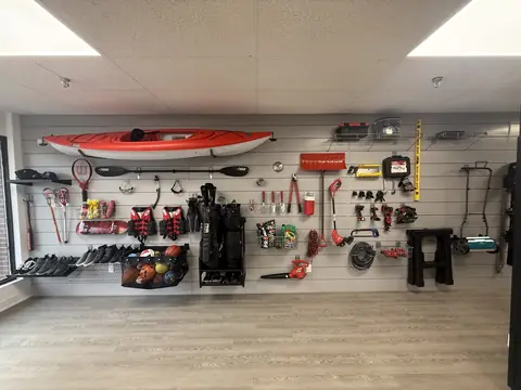 Slatwall wall with a red kayak mounted above and tools on hooks